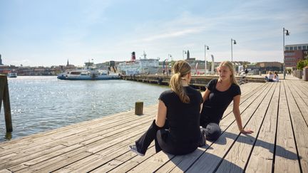 Två elever sitter på en brygga.