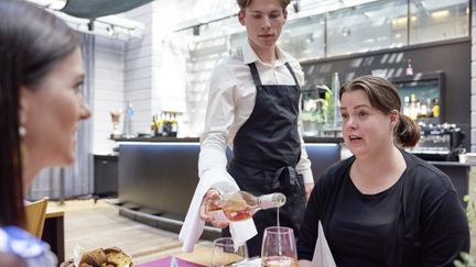 Elev som serverar två personer vid ett bord. 
