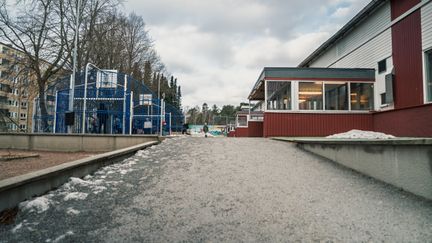 En gågata med multiarena på ena sidan och en skolbyggnad på andra sidan.