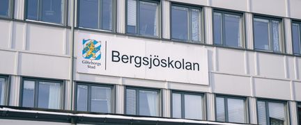 Bergsjöskolans skylt på huvudbyggnaden med entrén i bakgrunden.