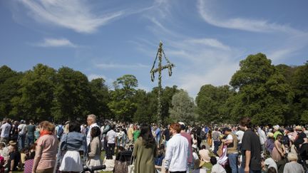 Människor som dansar runt en midsommarstång.