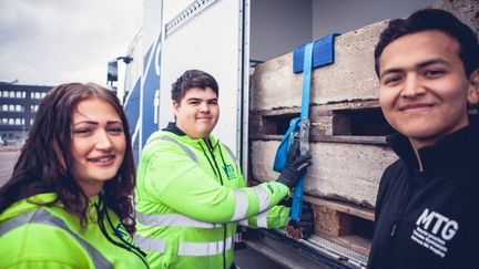 Elever vid en lastbil kollar lasten.