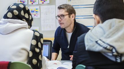 Två elever och en vuxen i en lärsituation i ett klassrum. 