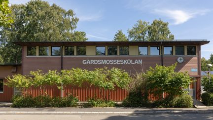 En röd skolbyggnad med texten Gärdsmosseskolan på fasaden.