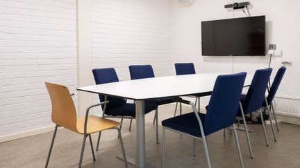 Möteslokal med tv-skärm och bord med stolar