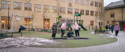 En lekplats framför Karl Johansskolan med några barn i bakgrunden.