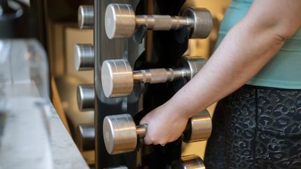 En hand som tar en hantel från sitt ställ.