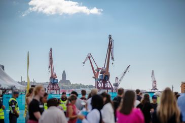 Folksamling på evenemang vid Göta älv med Göteborgs hamn och kranar i bakgrunden.