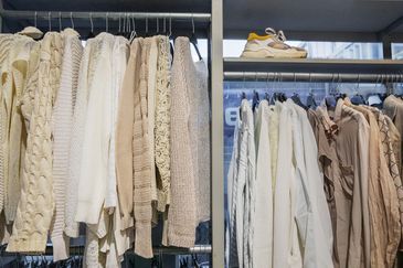 Ljusa kläder och skor hänger i en second hand-butik.