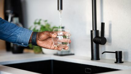 På bilden syns en hand som tappar upp kranvatten i ett glas.