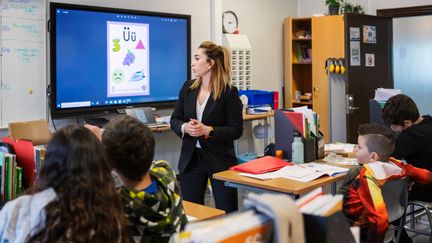 Elever och lärare i ett klassrum. De går igenom bokstaven Üü på tavlan. 