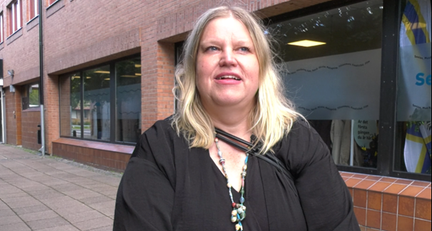 Kvinna med ljust hår står ute på gatan och pratar.