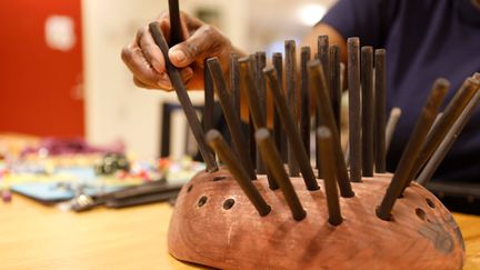 En person sätter pinnar i en oval träbit.