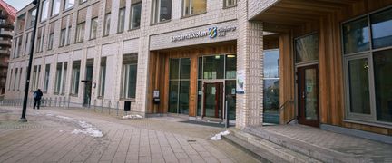 Huvudentrén till Sandarnaskolan med skolans skylt. I bakgrunden syns en person.