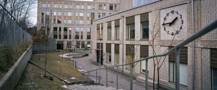Överblick av Sandarnaskolans byggnader med några träd och en trappa i bakgrunden.