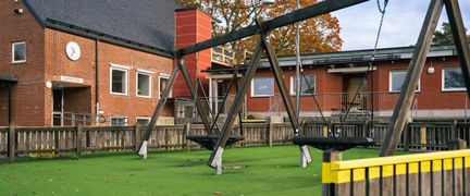 En lekplats med ett par gungor framför Hovåsskolan.