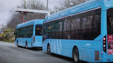 Två bussar vid en laddstation