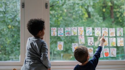  Två barn vid ett fönster som tittar på uppsatta bokstäver.