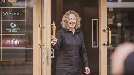 Leende person öppnar en dörr. På dörren står det bland annat Business Region Göteborg.