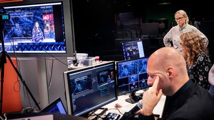 Flera datorer som visar en sändning. Personer sitter och tittar på skärmarna. 