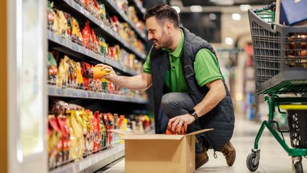 En person fyller på varor i en hylla.