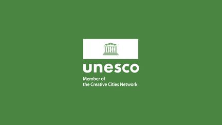 Unescos symbol för medlemskap i de kreativa städerna på grön botten.