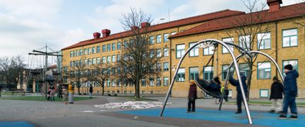 En grupp elever som står runt en gunga på en skolgård.