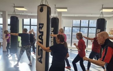 Flera kvinnor och män som tränar boxning i en ljus träningslokal.