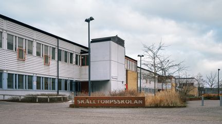 En skolbyggnad med en skylt i cortenstål framför sig med texten Skälltorpsskolan