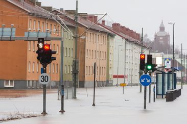 En översvämmad stadsgata. Mitt i vattnet står trafikljus och vägmärken. 