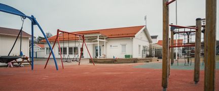 En lekplats med klätterställningar och gungor framför Asperöskolan.