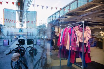 Ett butiksfönster med begagnade kläder. En cykel är parkerad bredvid fönstret.