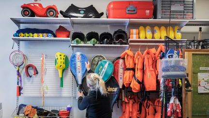 En hylla med fritidsartiklar som flytvästar, tennisrack och hjälmar