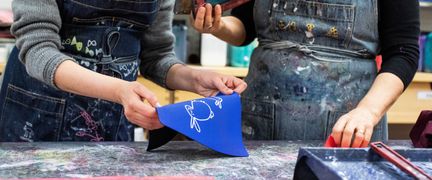 Två personer gör textiltryck.