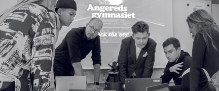 Elever och lärare står lutade över en laptop och tittar på bildskärmenv vid en presentation om Angeredsgymnasiet.