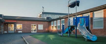 En rutschkana utanför Kannebäcksskolan med en skolbyggnad i bakgrunden.