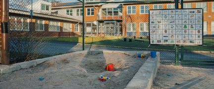 En sandlåda utanför Kannebäcksskolan med leksaker utspridda och en tavla i bakgrunden.