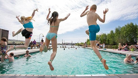 Tre ungdomar på väg att hoppa i en turkos pool