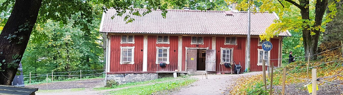 Bild på Stora Torps Stall, en 1800-talsbyggnad med röd fasad och vita knutar. 