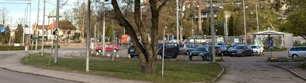 En parkeringsplats med bilar, träd i förgrunden