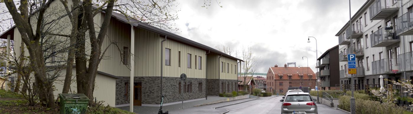 Förskolebyggnad med grått tegel och ljus fasad. På gatan syns en parkering och en elsparkcykel.