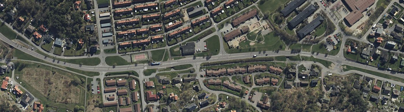 Flygvy över Önneredsvägen och kringliggande bostadsområden. På bilden syns en väg och kringliggande hustak.