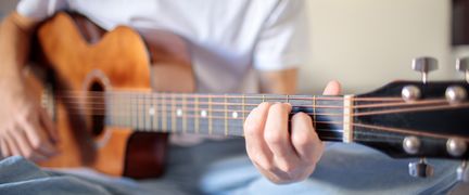 En person spelar gitarr.