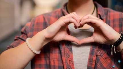 En person formar ett hjärta med sina fingrar.