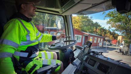 En sopbilschaufför i förarhytten på en sopbil.