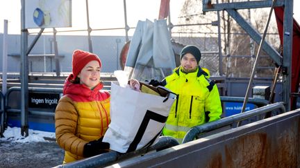Två personer slänger skräp på en återvinningscentral