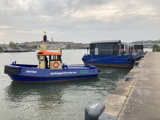 Återvinningspråmen ligger förtöjd vid en kaj längs Göta älv i Göteborg.