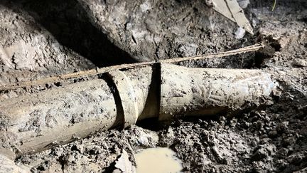 Ett betongrör för dricksvatten i lera. Röret har sprungit läck i böjen på grund av rörelser i marken.