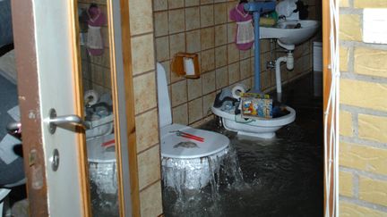 En översvämmad toalett. Vatten forsar ur toalettstolen trots att locket är stängt. 