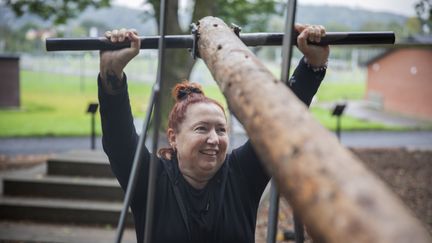 En person lyfter en stock över sitt huvud i ett utegym.